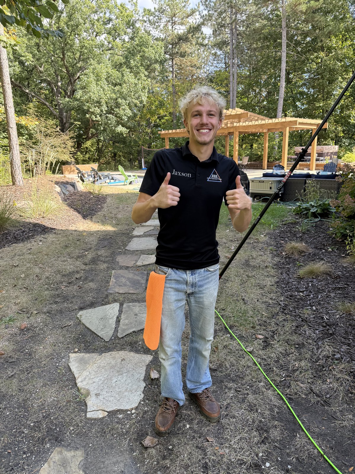 Jaxson, founder of JBL Exterior Pros, in a branded polo holding a water-fed pole